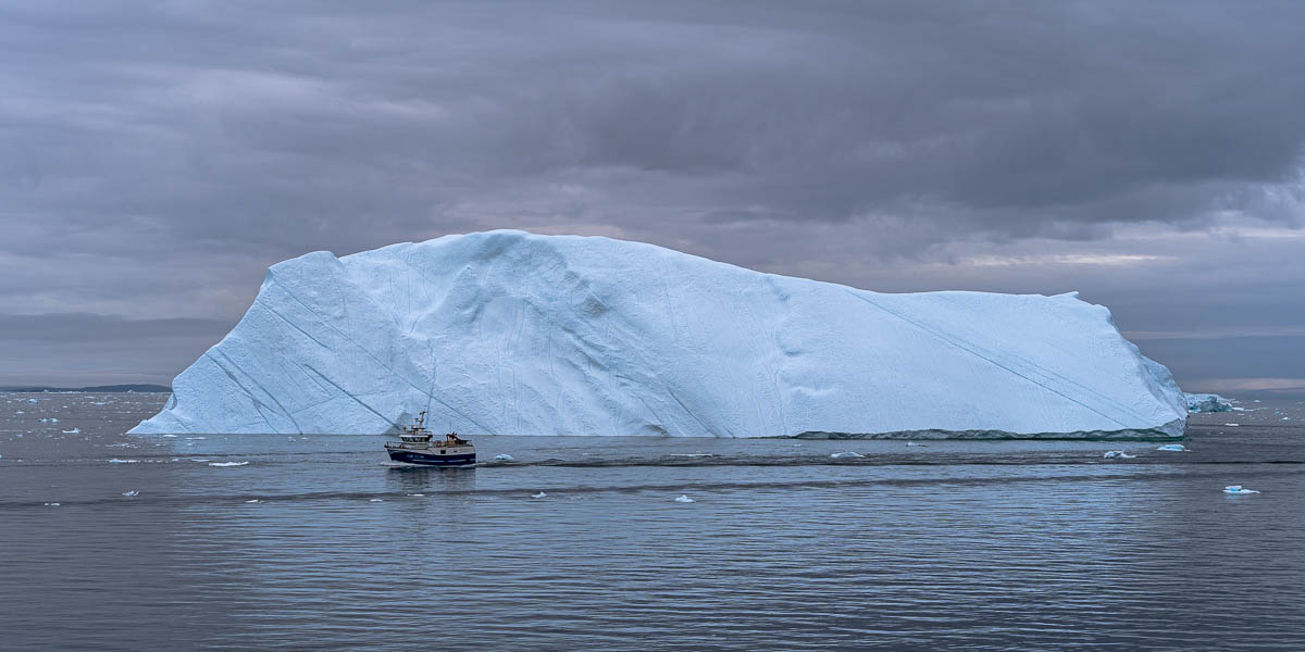 Entrée du fjord d'Ilulissat : iceberg et bateau de pêche